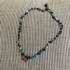 Handmade blue beaded necklace with silver butterfly charm and loop closure
